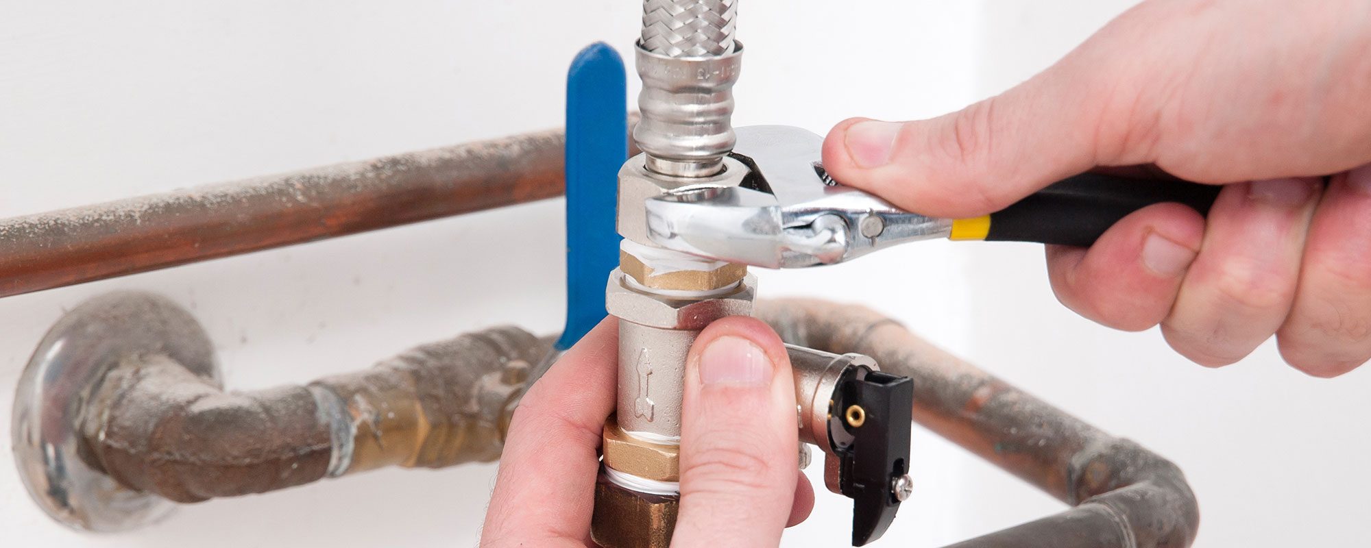 A person turning a wrench on a bolt representing the emergency plumbing services of John J. Cahill servicing Chicago, IL