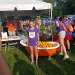 A girl standing by a tub of oranges, showing the community events attended by furnace repair company John J. Cahill Inc. in Evanston, IL